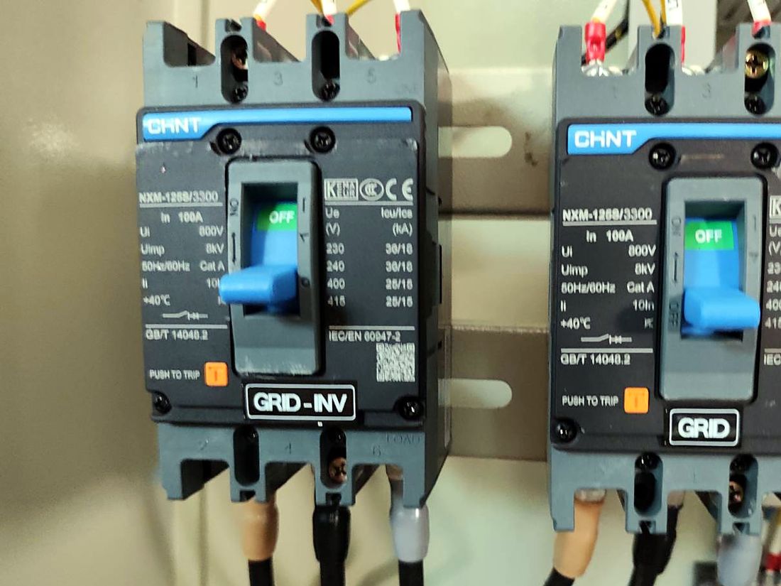 Two 100 A breakers labelled GRID-INV and GRID
